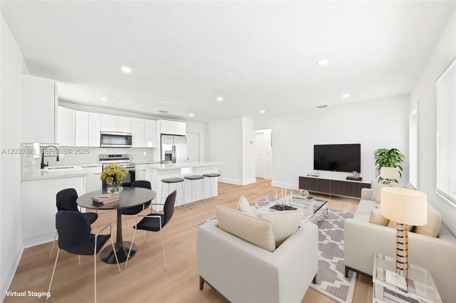 This is a virtually staged open-concept living room and kitchen with white cabinetry and flooring — 1491 NW 55th Ter, Miami FL 33142, MIAMI, FL