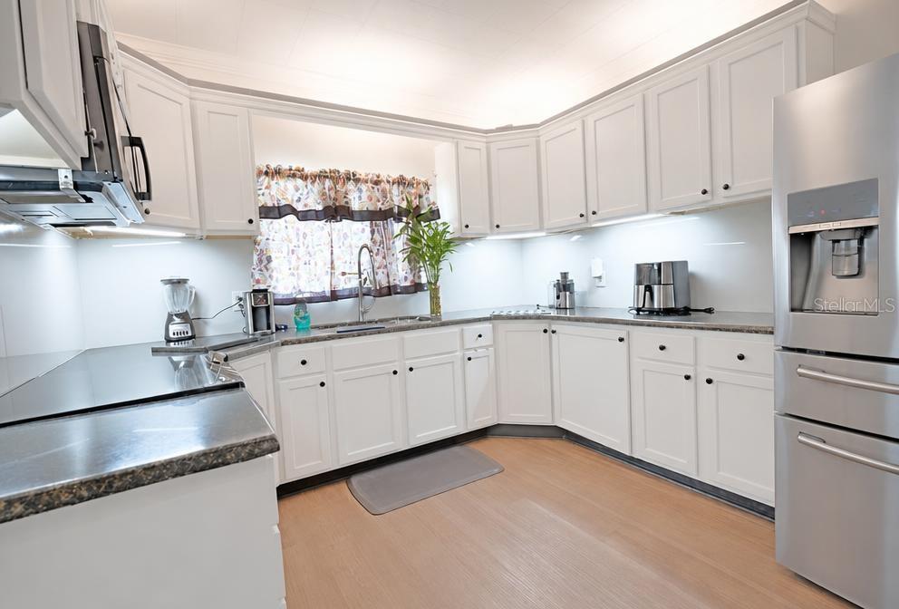 A kitchen with white cabinets, stainless steel appliances, and dark countertops on light wood flooring — 819 SAN JUAN BOULEVARD, ORLANDO, FL