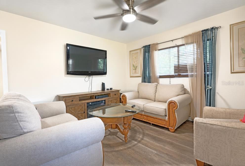 A living room features light-colored sofas, a glass-top coffee table, and a wall-mounted television — 819 SAN JUAN BOULEVARD, ORLANDO, FL