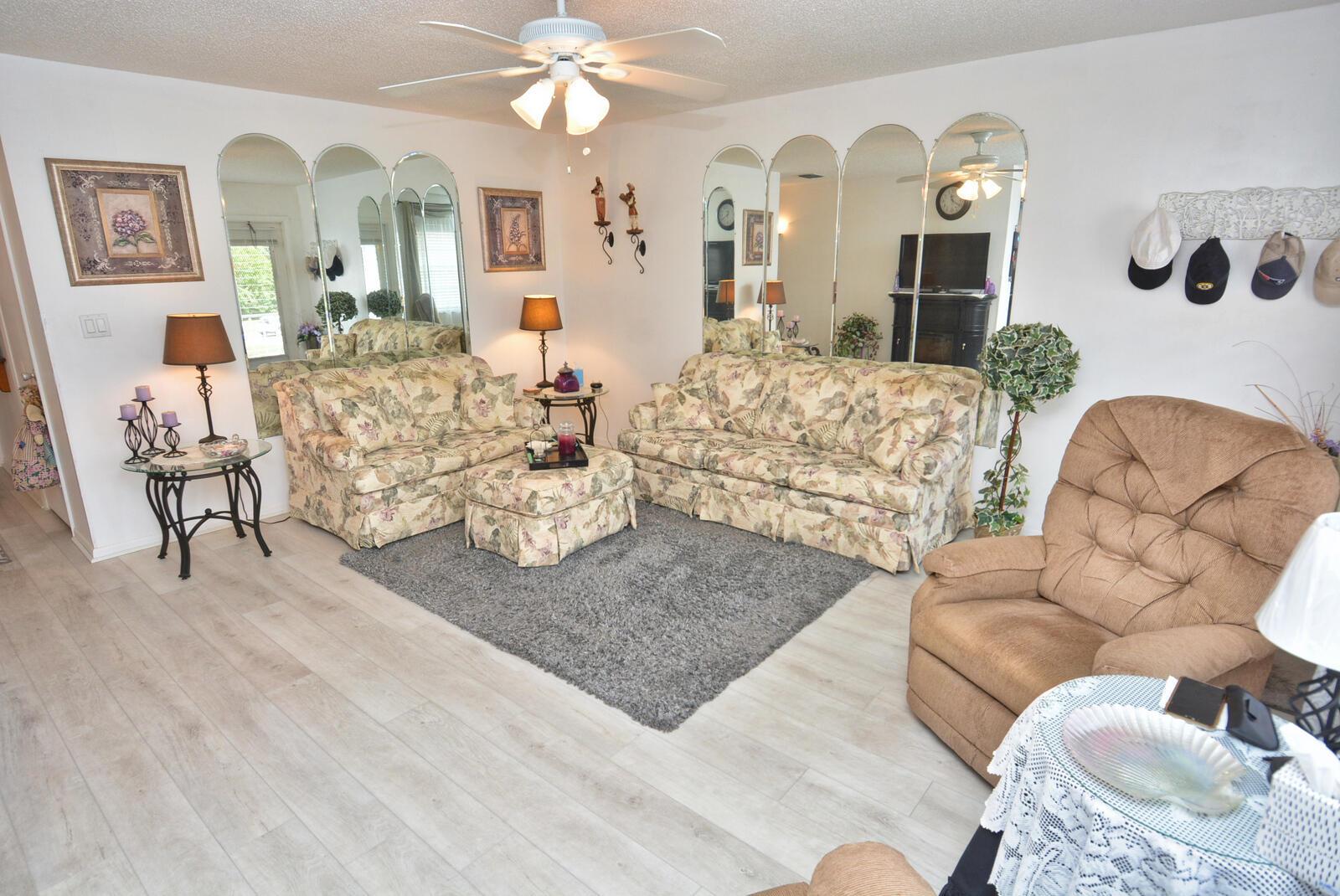 A living room features floral sofas, a grey area rug, and arched wall mirrors — 1225 NW 21st Street # 309, Stuart FL 34994, STUART, FL
