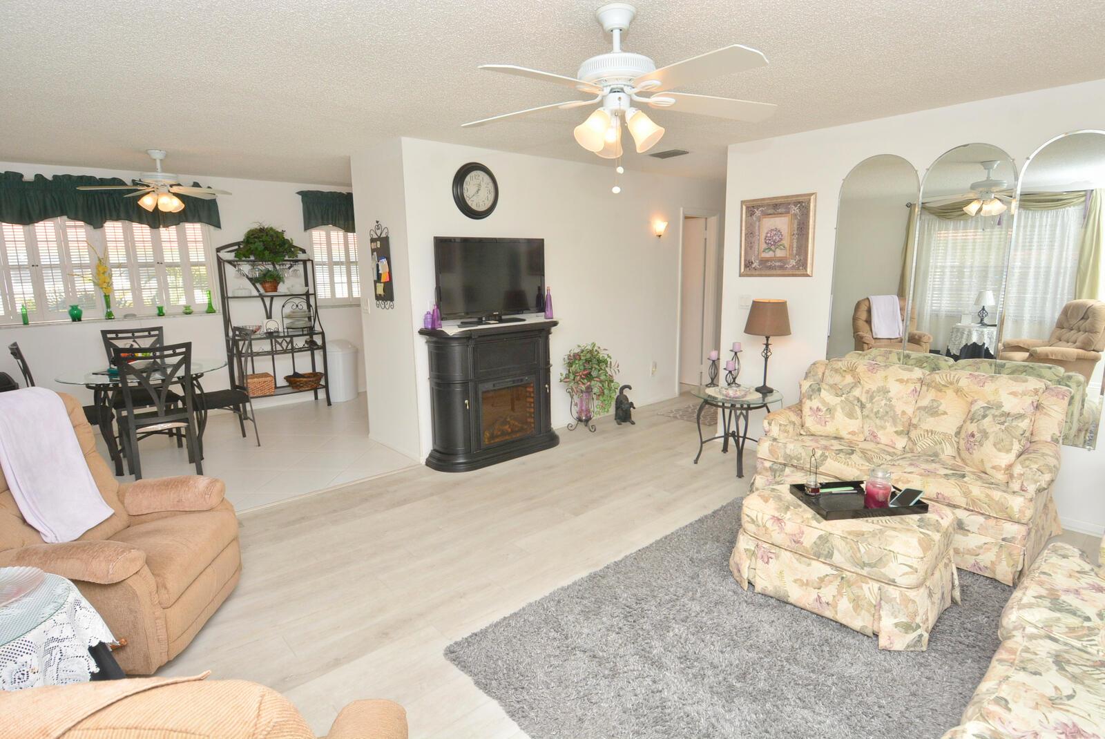 A living room with a floral sofa, fireplace, television, and dining area with tile floors — 1225 NW 21st Street # 309, Stuart FL 34994, STUART, FL