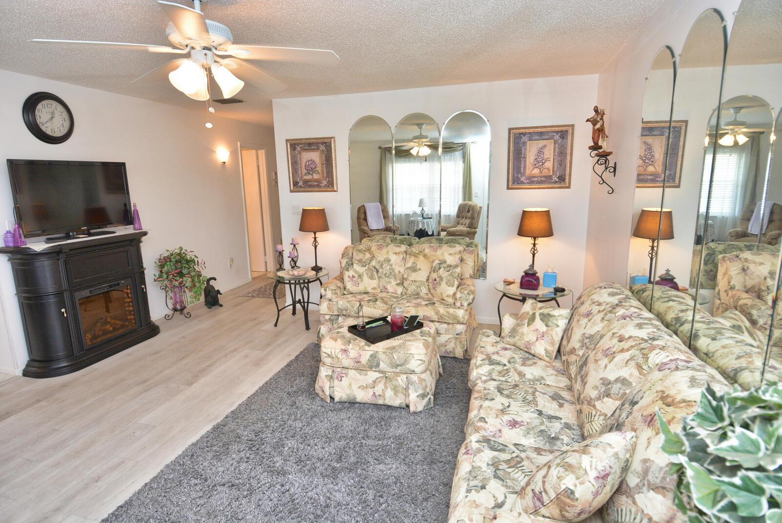 A living room features floral furniture, a fireplace, a gray rug, and arched wall mirrors — 1225 NW 21st Street # 309, Stuart FL 34994, STUART, FL