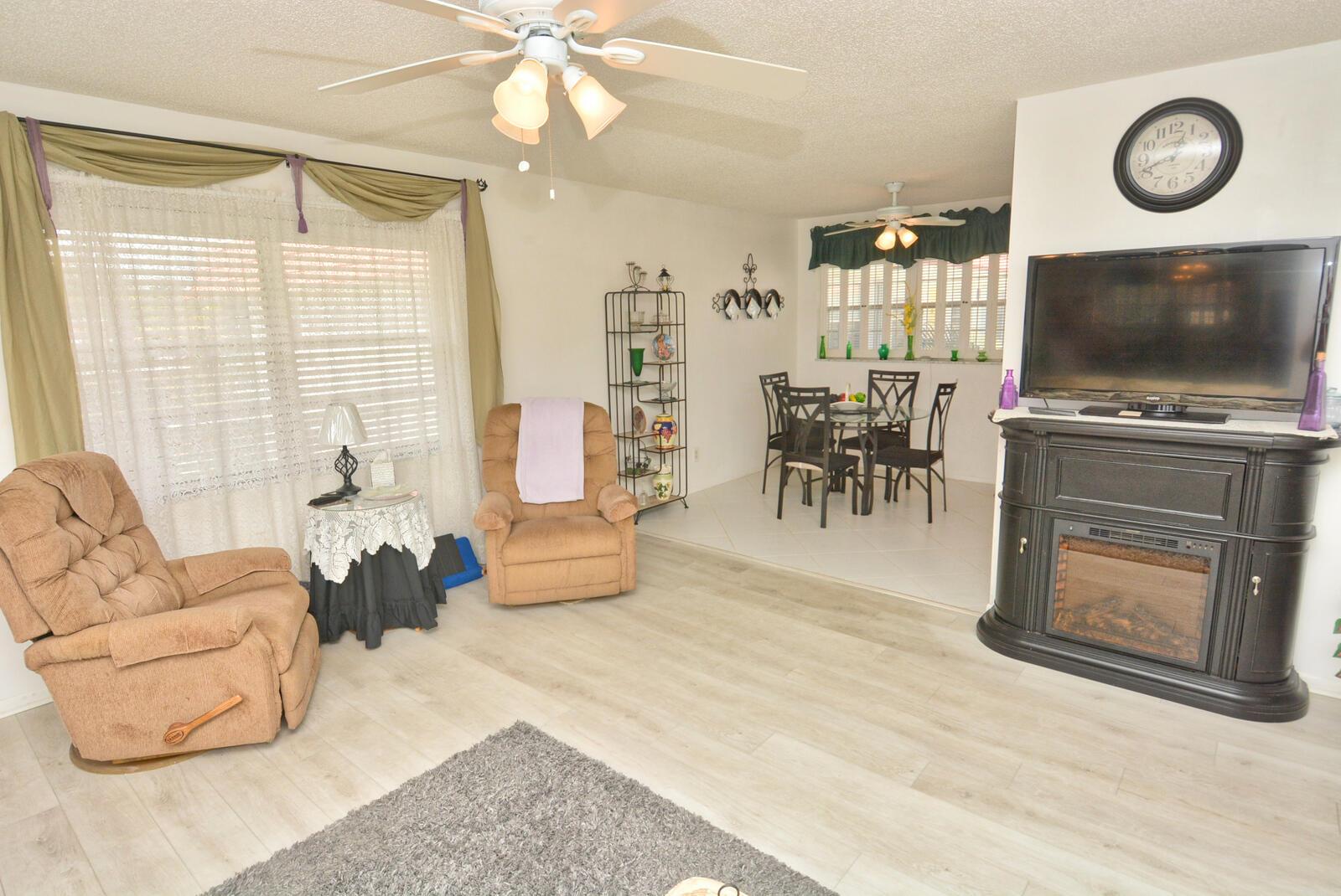A living room with light wood flooring, two recliners, a fireplace, and an adjacent dining area — 1225 NW 21st Street # 309, Stuart FL 34994, STUART, FL