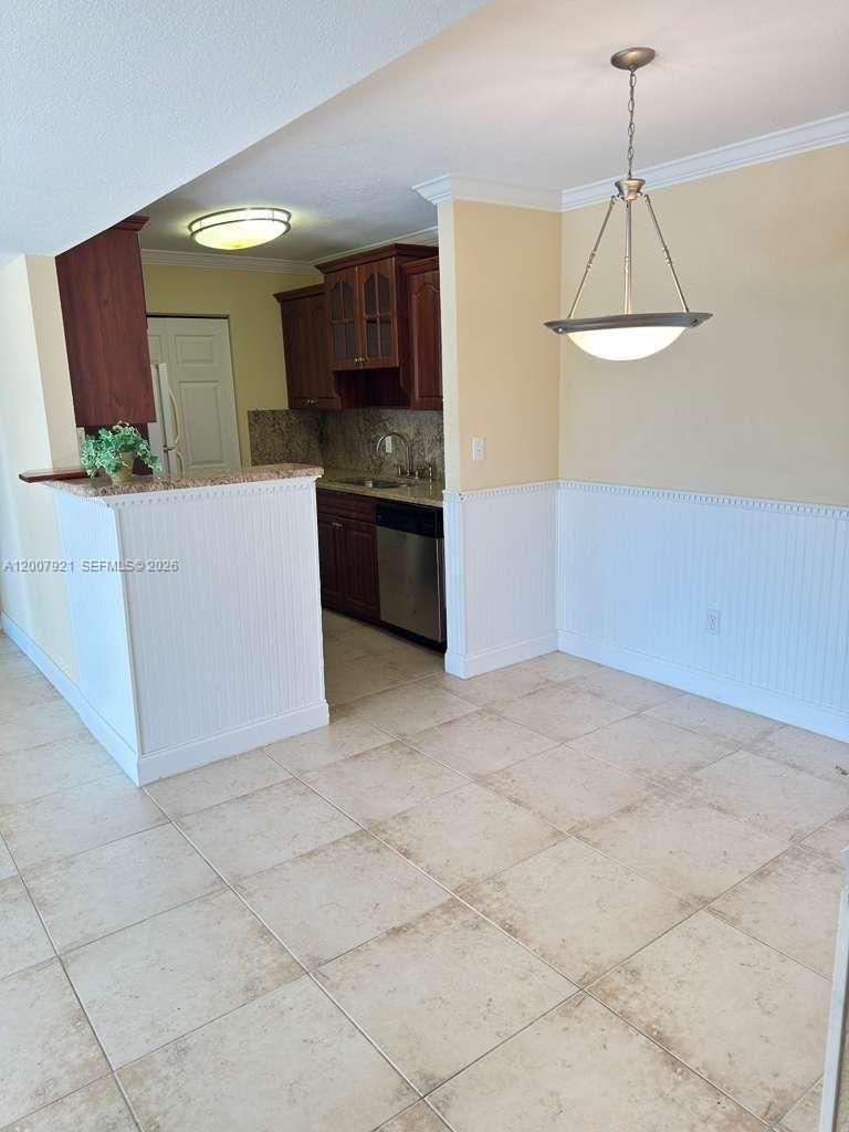 A kitchen with dark wood cabinets and a breakfast bar opens into a dining area — 455 ALT 19 S # 12, Palm Harbor FL 34683, PALM HARBOR, FL