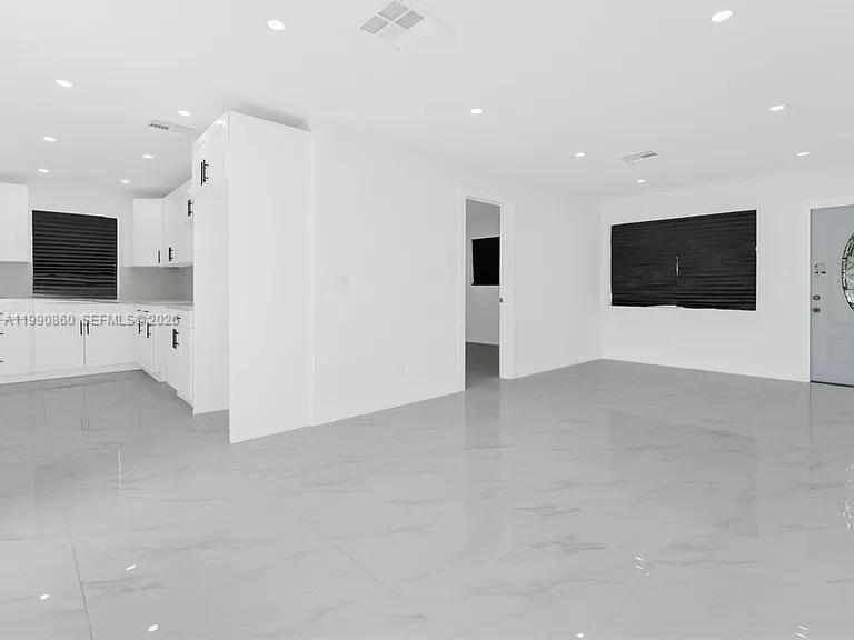 A bright, open-concept room features white kitchen cabinets, marble-patterned tile flooring, and recessed lighting — 4900 NW 14th St, Lauderhill FL 33313, LAUDERHILL, FL