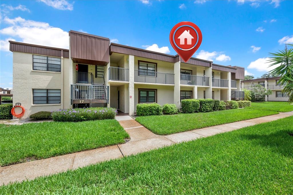 A two-story apartment building with a tan stucco exterior and a brown roof — 2400 WINDING CREEK BOULEVARD UNIT 17-203, CLEARWATER, FL