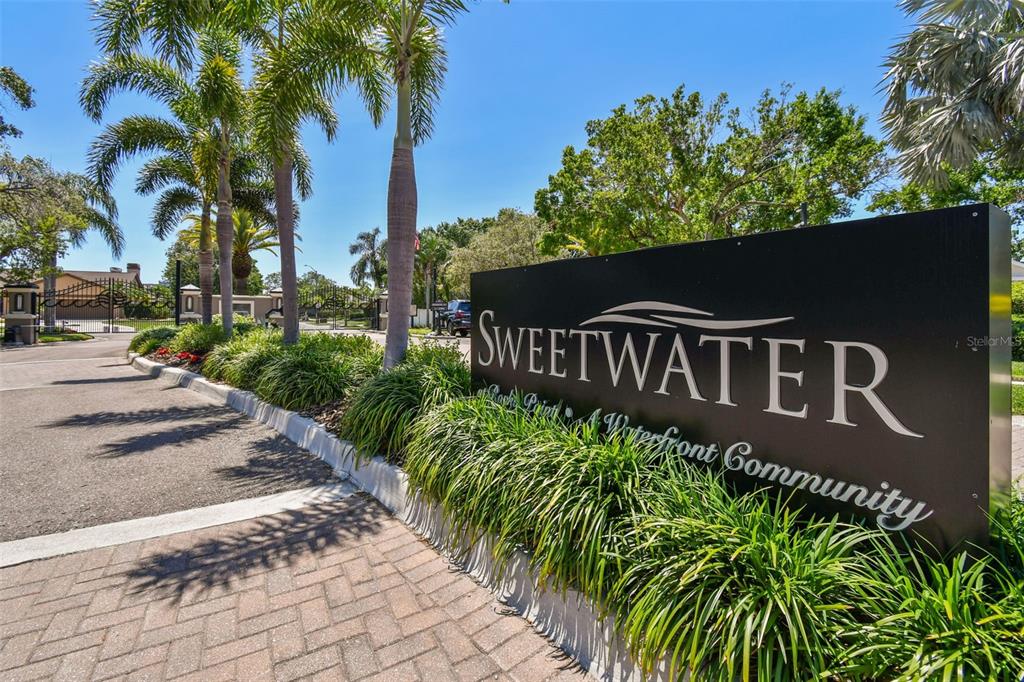A sign for a waterfront community named Sweetwater stands beside a paved entrance road — 4147 SALTWATER BOULEVARD, TAMPA, FL