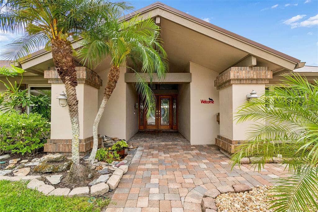 A paved walkway leads to the covered entryway of a house with palm trees — 4147 SALTWATER BOULEVARD, TAMPA, FL