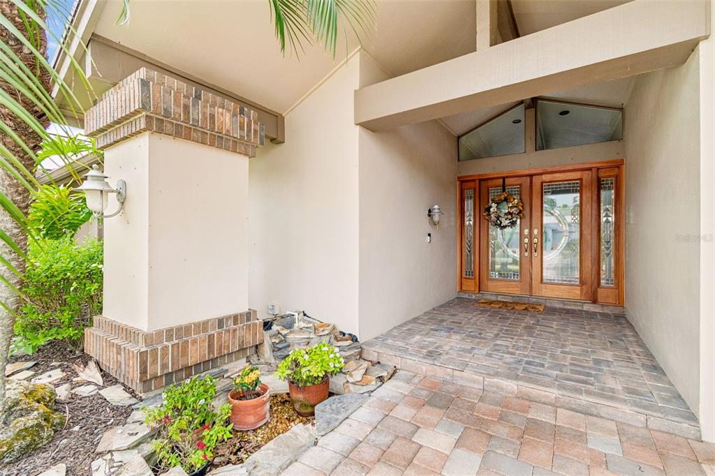 A covered entryway features a brick-paved floor, a double wooden door, and a brick pillar — 4147 SALTWATER BOULEVARD, TAMPA, FL