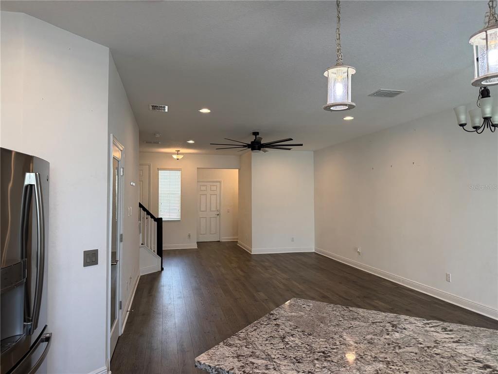An open-concept living area features dark wood flooring, a granite-topped island, and pendant lighting — 2444 FOGGY CREEK CIRCLE, CLEARWATER, FL