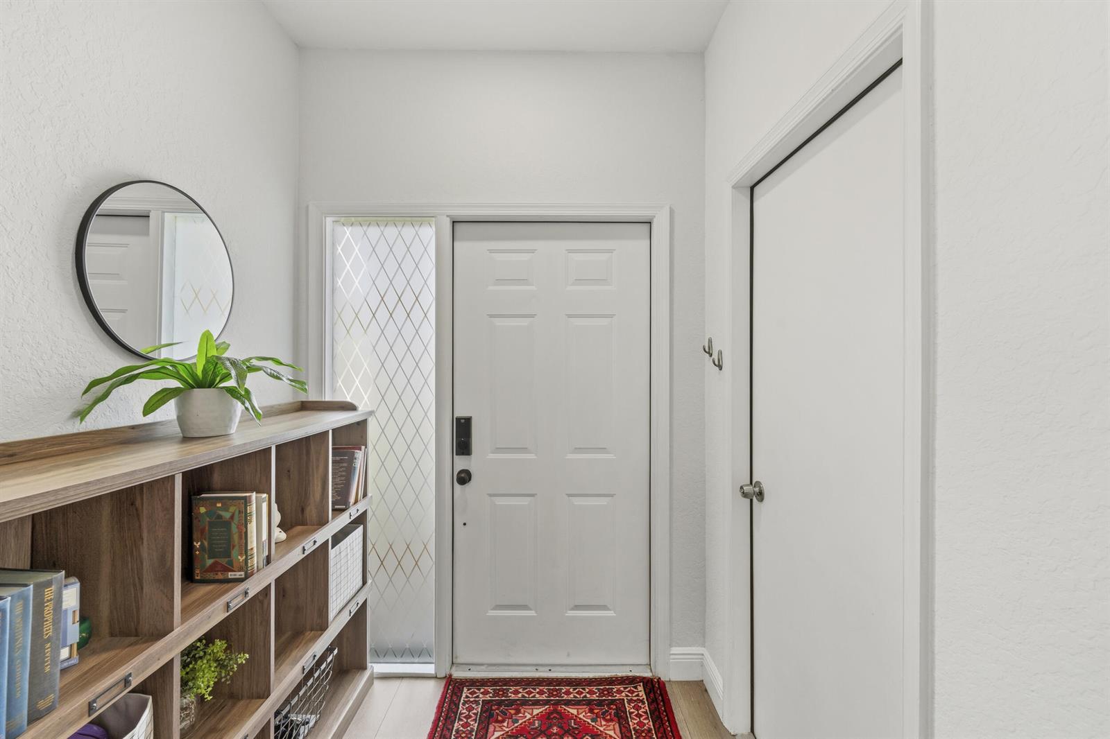 A bright entryway features a white front door, a wooden bookshelf, and a round mirror — 7015 SE Cutler Trail SE, Stuart FL 34997, STUART, FL