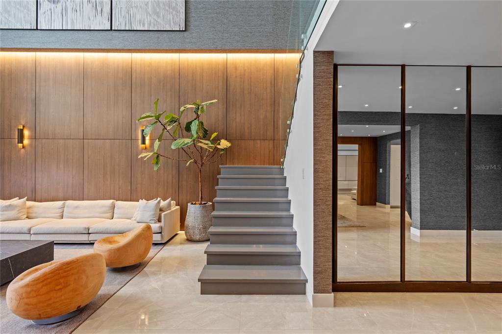 A modern living room features a wooden accent wall, a staircase, and mirrored sliding doors — 105 ORTEGON AVENUE UNIT PH1, GUAYNABO, PR
