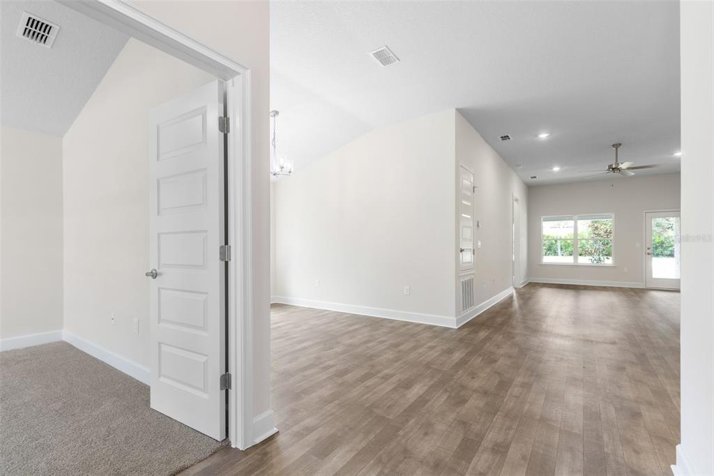 An interior view shows a carpeted room opening into a living area with wood-look flooring — 7 ZIRCON COURT, PALM COAST, FL