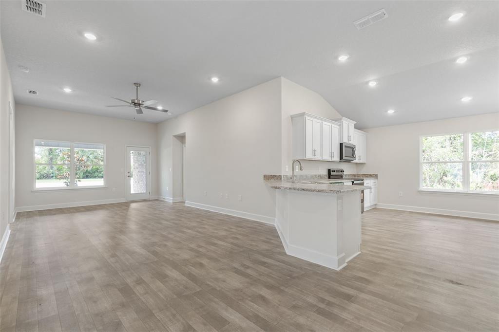 An open-concept kitchen and living area with white cabinets, light flooring, and recessed lighting — 7 ZIRCON COURT, PALM COAST, FL