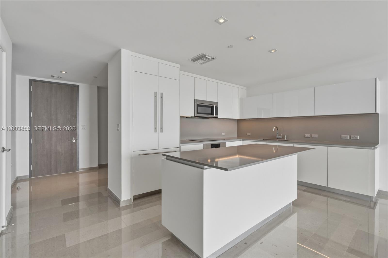 A modern kitchen features white cabinetry, a central island, and polished tile flooring — 88 SW 7th St # 3710, Miami FL 33130, MIAMI, FL