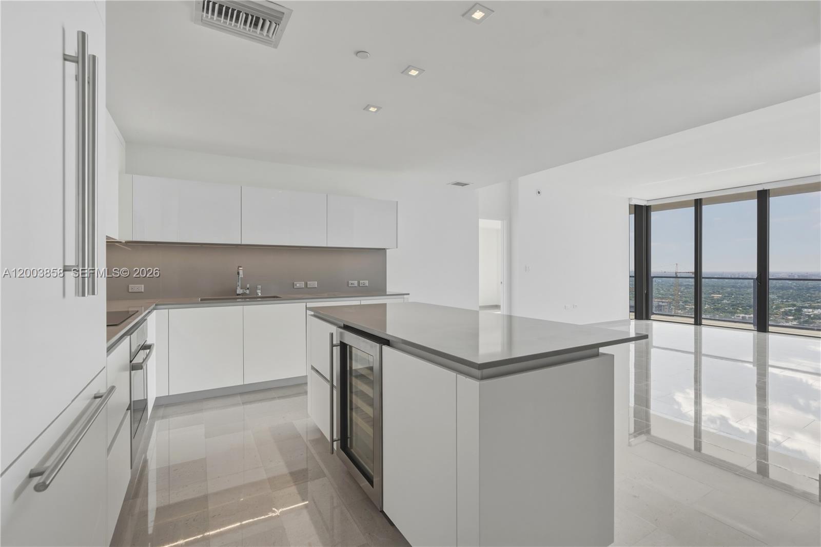 A modern white kitchen features a central island, stainless steel appliances, and floor-to-ceiling windows — 88 SW 7th St # 3710, Miami FL 33130, MIAMI, FL