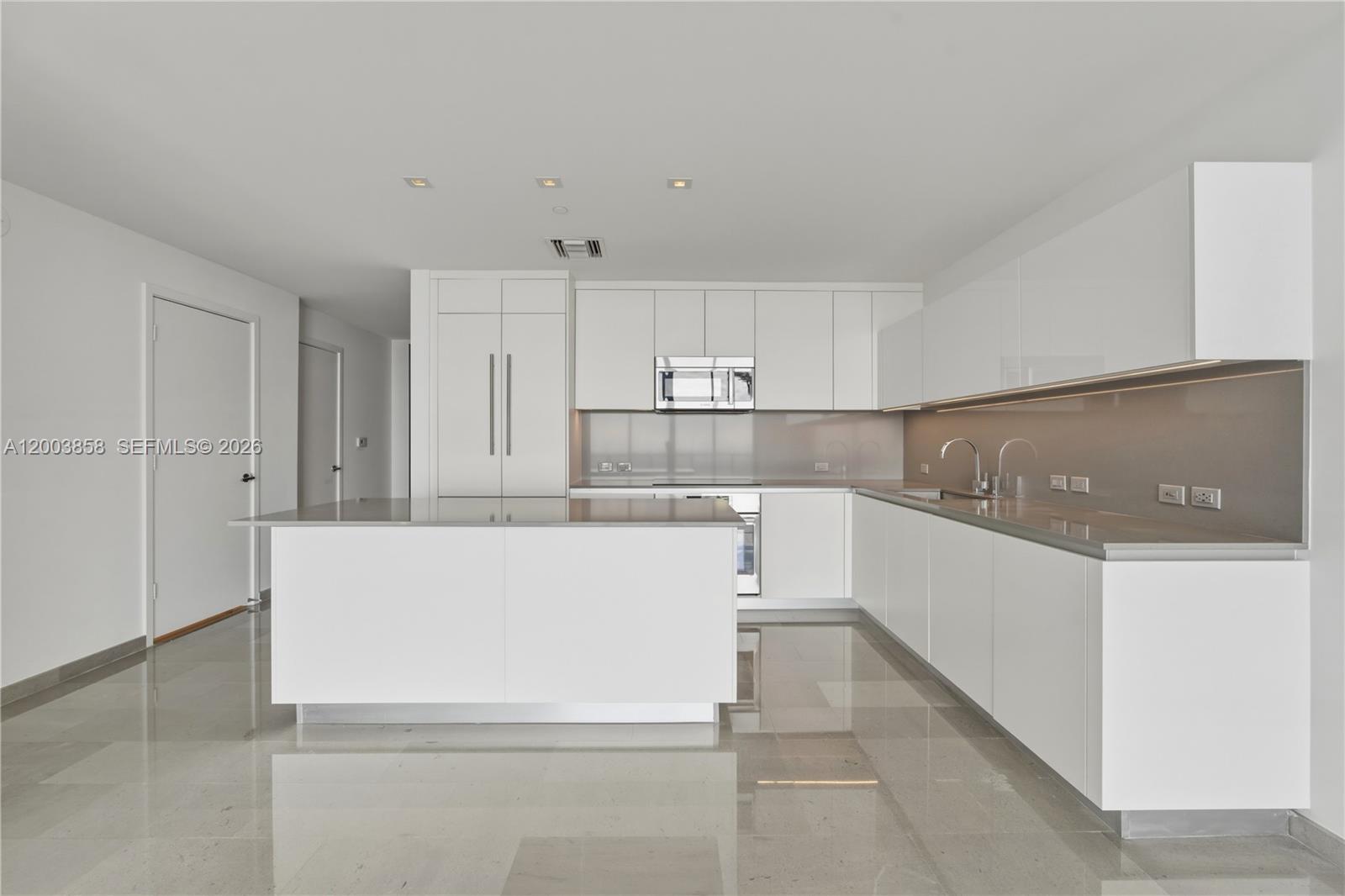 A modern white kitchen features a central island, glossy cabinets, and polished tile flooring — 88 SW 7th St # 3710, Miami FL 33130, MIAMI, FL