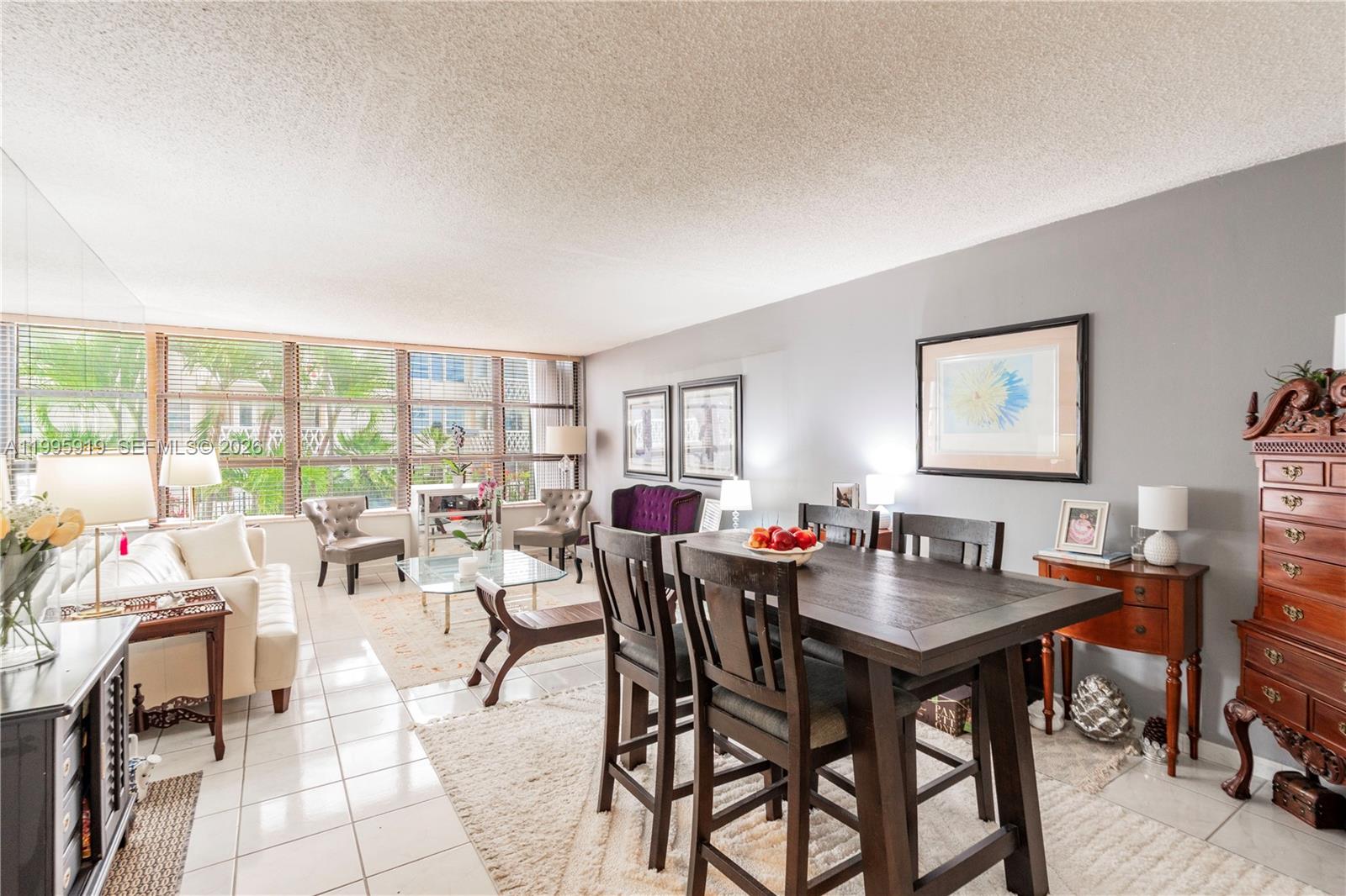 A living and dining area features tile floors, a large window, and dark wood furniture — 1440 Brickell Bay Dr # 203, Miami FL 33131, MIAMI, FL