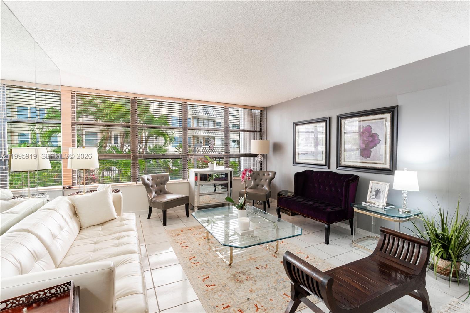 A living room features white tile floors, a glass coffee table, and a purple settee — 1440 Brickell Bay Dr # 203, Miami FL 33131, MIAMI, FL