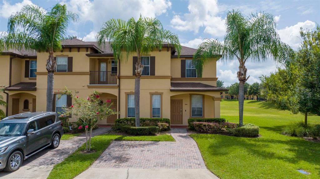 A two-story tan townhouse with a brick driveway and two palm trees in the front — 206 BERGAMO DRIVE, DAVENPORT, FL
