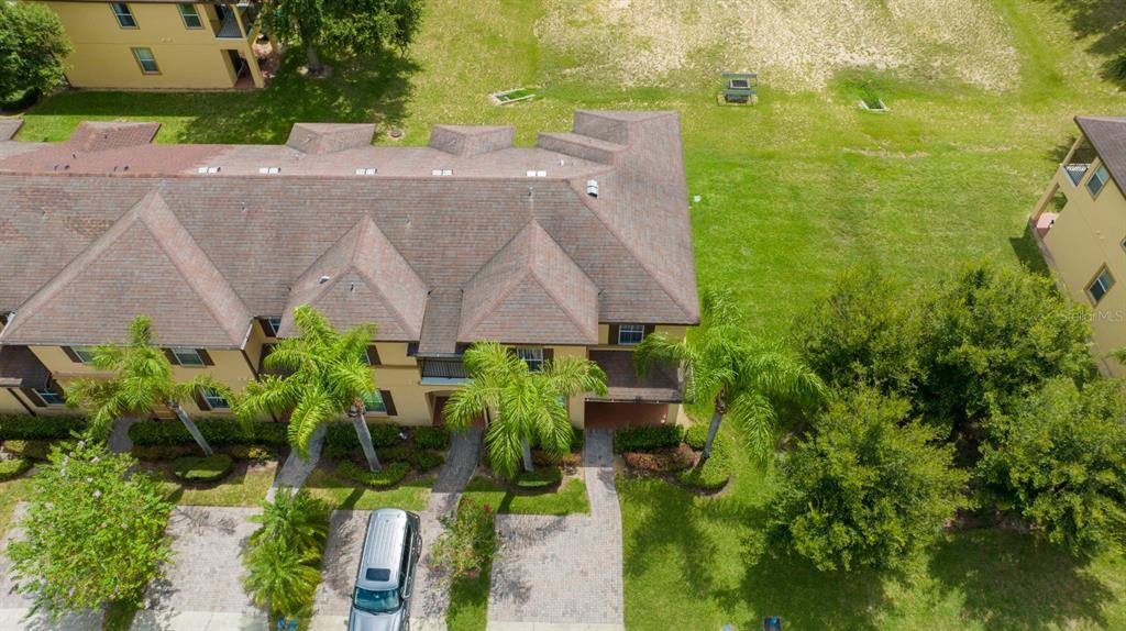 An aerial view shows a multi-unit residential building with a brown shingled roof and landscaping — 206 BERGAMO DRIVE, DAVENPORT, FL