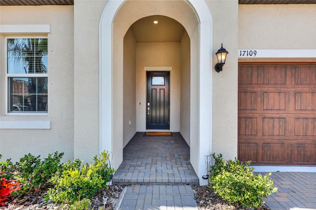 A front entryway features a dark door, a brick walkway, and a garage door — 17109 STAR BANKS STREET, WIMAUMA, FL