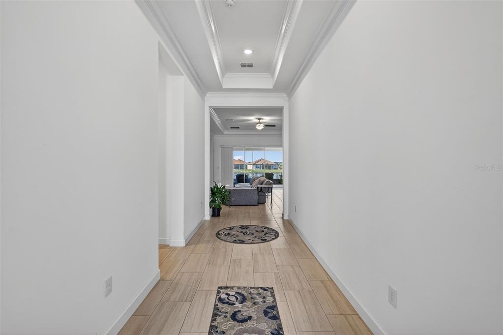 A bright hallway with tile flooring leads to a living area with a view outside — 17109 STAR BANKS STREET, WIMAUMA, FL