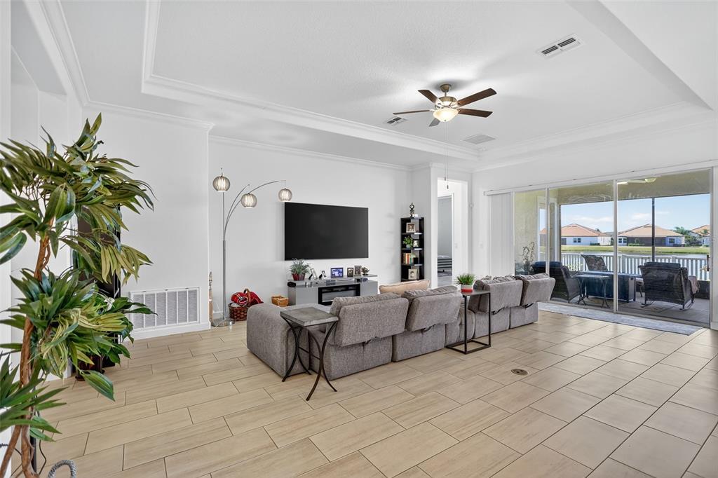 A spacious living room features tile flooring, a large sectional sofa, and sliding glass doors — 17109 STAR BANKS STREET, WIMAUMA, FL