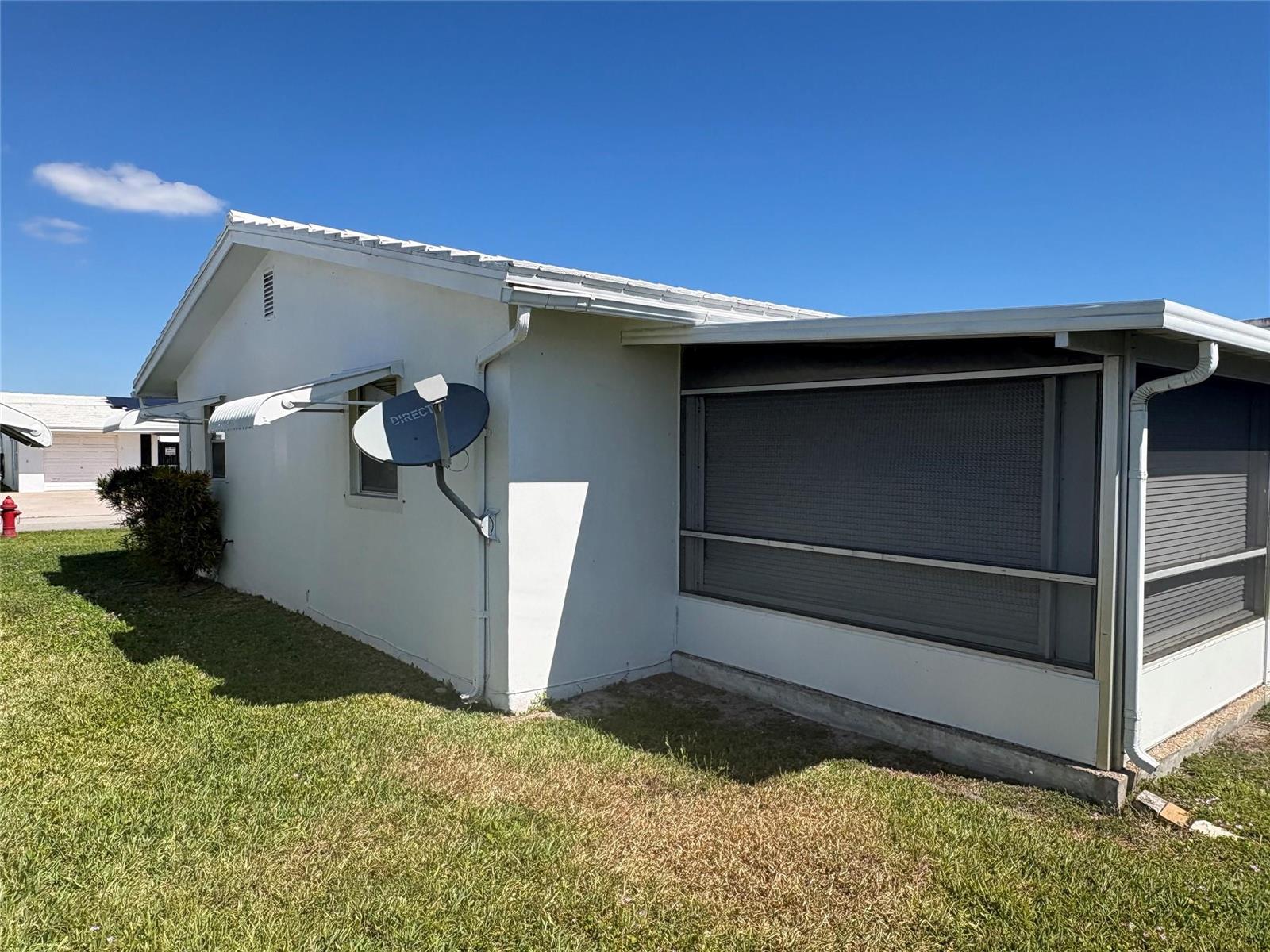 The exterior of a white house features a screened-in porch and a satellite dish — 2392 SW 13th Terrace, Boynton Beach FL 33426, BOYNTON BEACH, FL