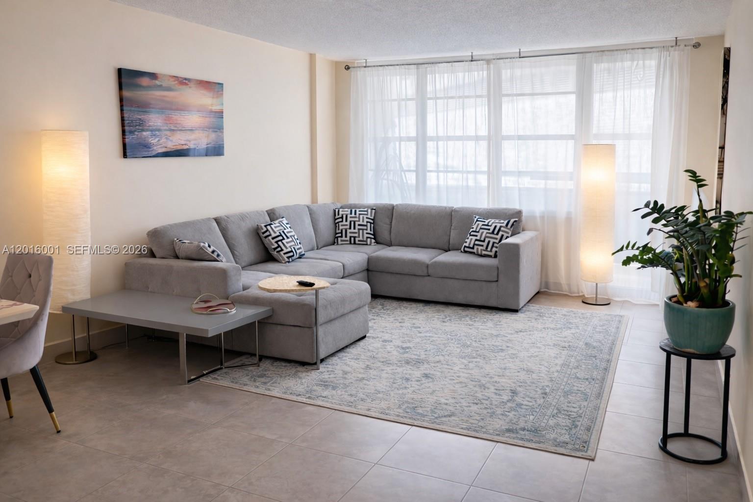 A living room features a gray sectional sofa, a patterned area rug, and two floor lamps — 3725 S Ocean Dr # 1015, Hollywood FL 33019, HOLLYWOOD, FL