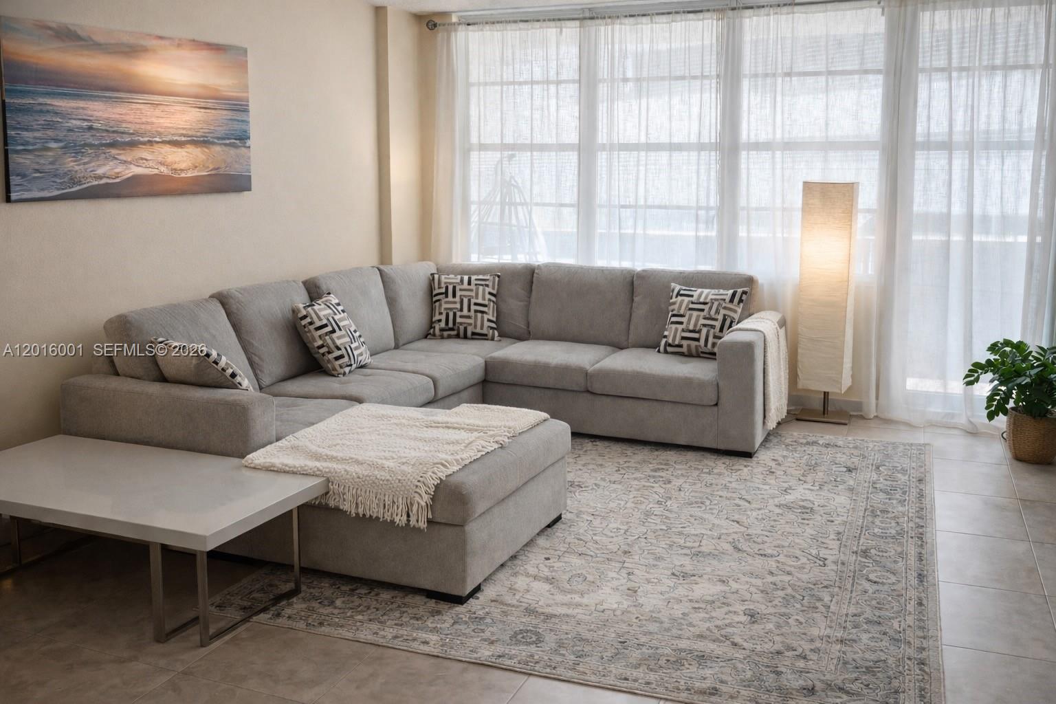 A living room features a grey sectional sofa, a white coffee table, and a patterned rug — 3725 S Ocean Dr # 1015, Hollywood FL 33019, HOLLYWOOD, FL