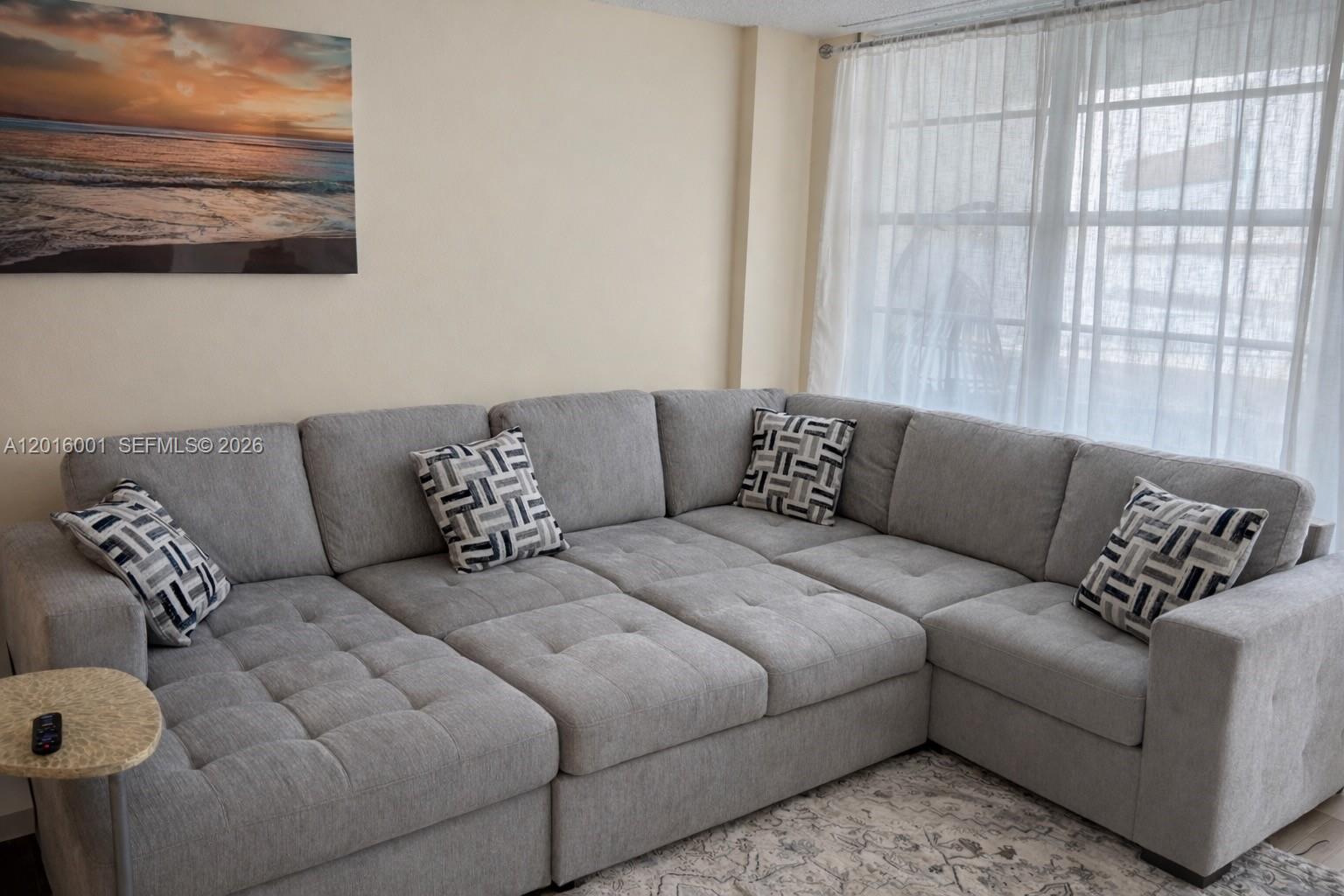 A light gray sectional sofa with patterned throw pillows sits in a living room — 3725 S Ocean Dr # 1015, Hollywood FL 33019, HOLLYWOOD, FL