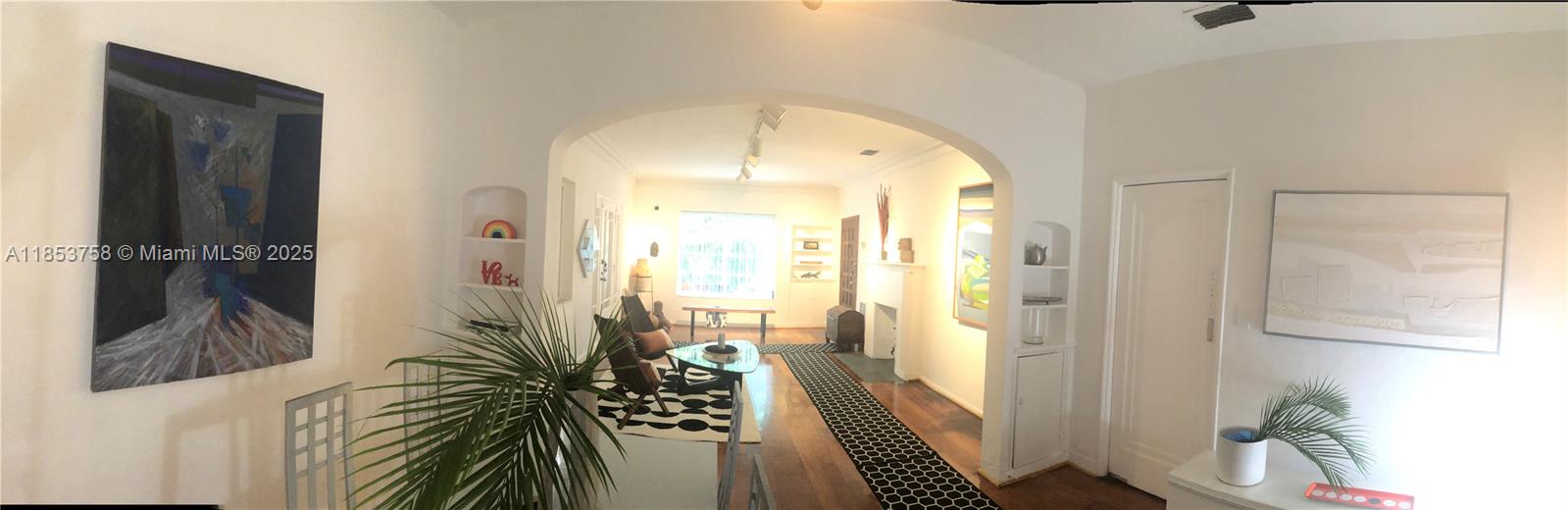 A living room features an arched entryway, hardwood floors, a patterned rug, and wall art — 1619 SW 13th St, Miami FL 33145, MIAMI, FL