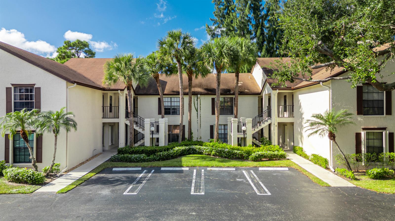 An exterior view of a two-story apartment building with palm trees and a parking lot — 3233 Perimeter Drive # 2511, FL 33467, FL