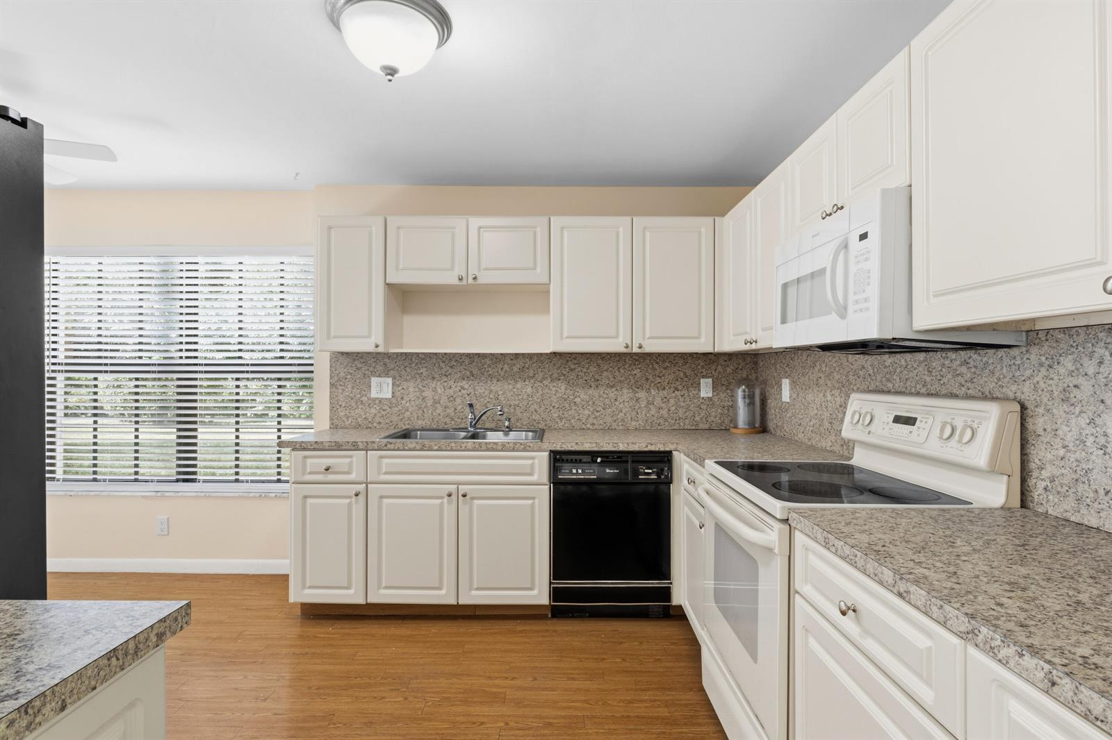 A kitchen features white cabinets, granite countertops, a black dishwasher, and a white electric range — 3233 Perimeter Drive # 2511, FL 33467, FL