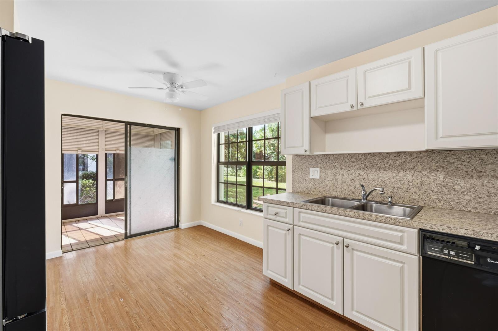 A kitchen with white cabinets, granite-look countertops, wood-style flooring, and a sliding glass door — 3233 Perimeter Drive # 2511, FL 33467, FL