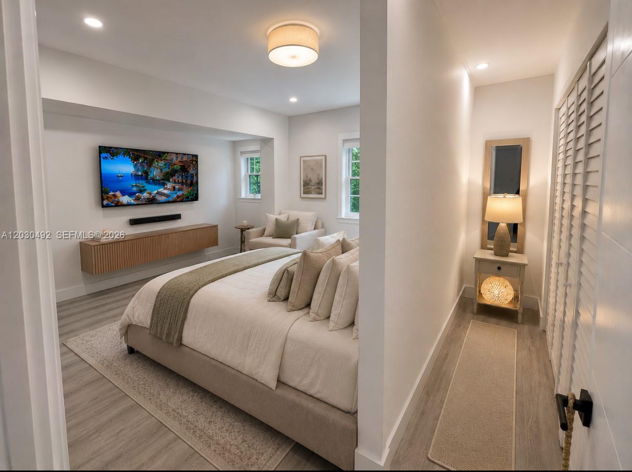 A bedroom features a wall-mounted television, a floating wooden console, and a neutral color palette — 1905 Alamanda Dr, North Miami FL 33181, NORTH MIAMI, FL