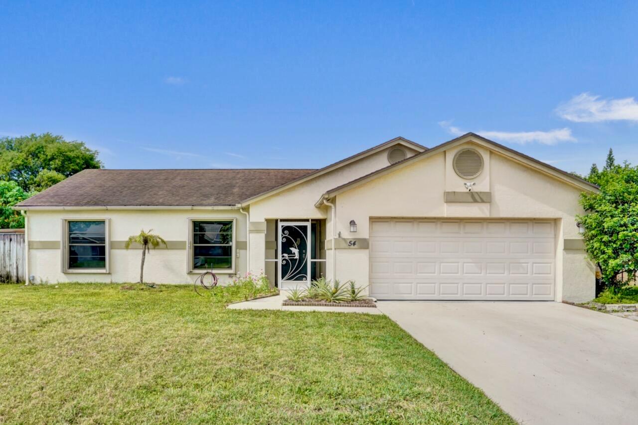 A single-story house with a beige stucco exterior, a two-car garage, and a front lawn — 54 Cedar Circle, Boynton Beach FL 33436, BOYNTON BEACH, FL