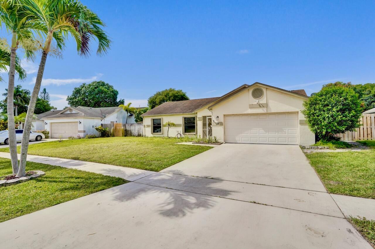 A single-story house with a beige exterior, a two-car garage, and a concrete driveway — 54 Cedar Circle, Boynton Beach FL 33436, BOYNTON BEACH, FL