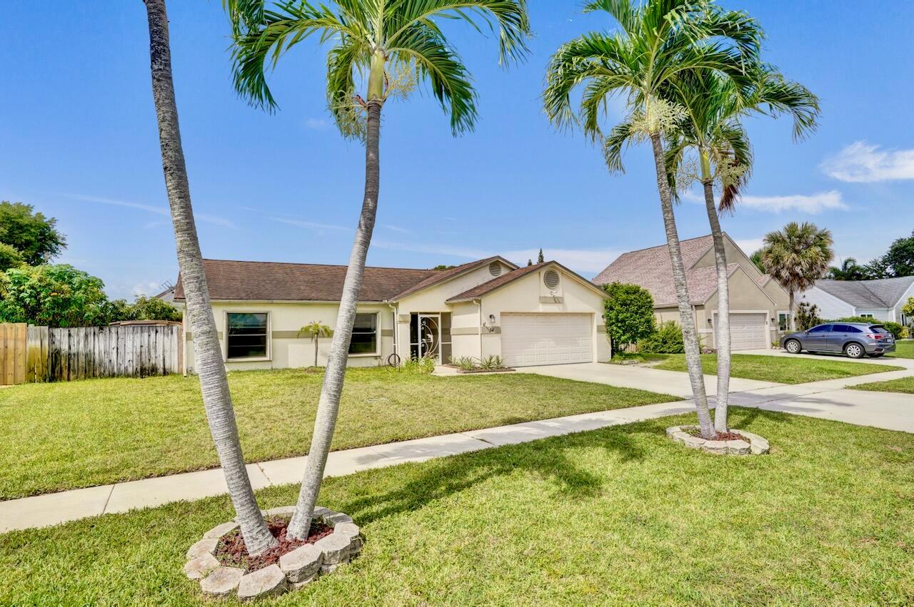 A single-story house with a two-car garage and palm trees in the front yard — 54 Cedar Circle, Boynton Beach FL 33436, BOYNTON BEACH, FL