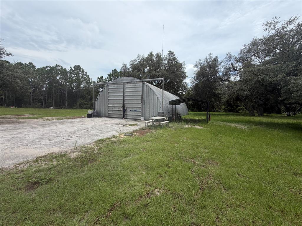A metal Quonset hut sits on a concrete pad in a grassy, wooded lot — 6828 STATE ROAD 33, CLERMONT, FL