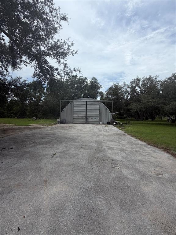 A large, arched metal hangar building sits at the end of a paved driveway — 6828 STATE ROAD 33, CLERMONT, FL