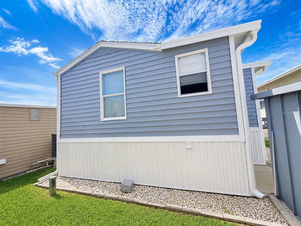 The exterior of a light blue mobile home features white skirting and two windows — 2215 73RD STREET E UNIT 334, PALMETTO, FL