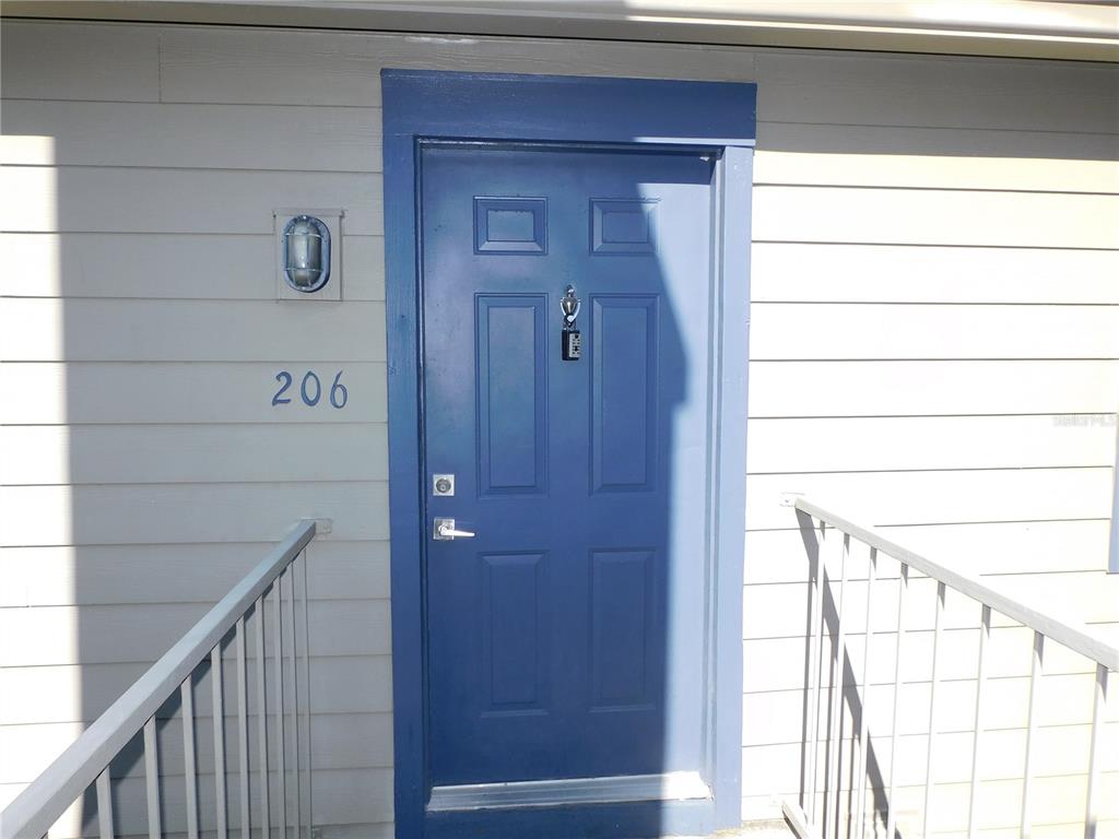 A blue front door with a lockbox and the number 206 on the exterior wall — 936 BIRMINGHAM COURT UNIT 206, LAKE MARY, FL