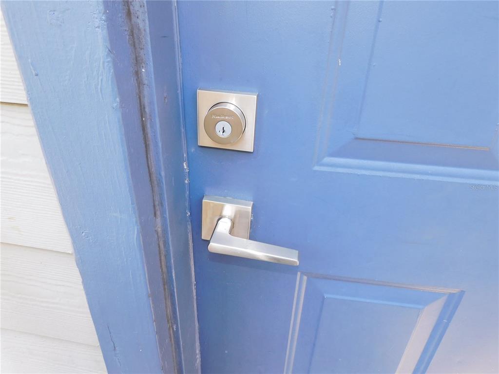 A close-up view of a blue door with a silver handle and a Kwikset deadbolt — 936 BIRMINGHAM COURT UNIT 206, LAKE MARY, FL