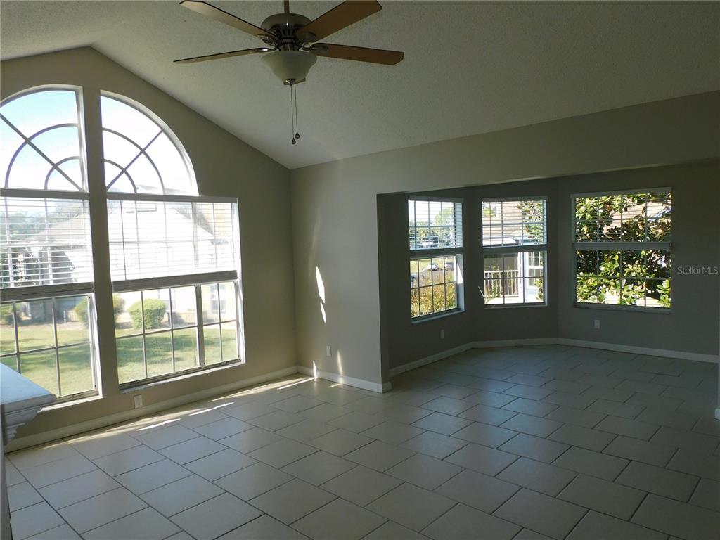 A bright living room features light tile flooring, a vaulted ceiling, and large arched windows — 936 BIRMINGHAM COURT UNIT 206, LAKE MARY, FL