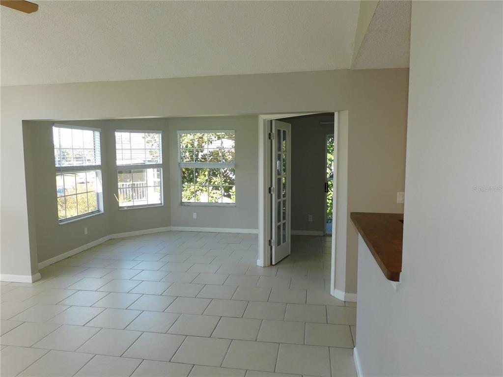 A bright room with light tile flooring, a bay window, and a glass-paneled interior door — 936 BIRMINGHAM COURT UNIT 206, LAKE MARY, FL