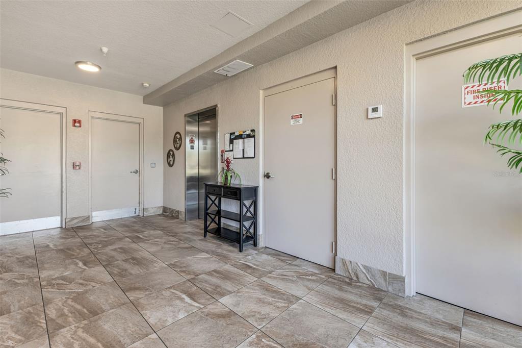A tiled hallway features an elevator, a console table, and several doors — 3322 PURPLE MARTIN DRIVE UNIT 126, PUNTA GORDA, FL