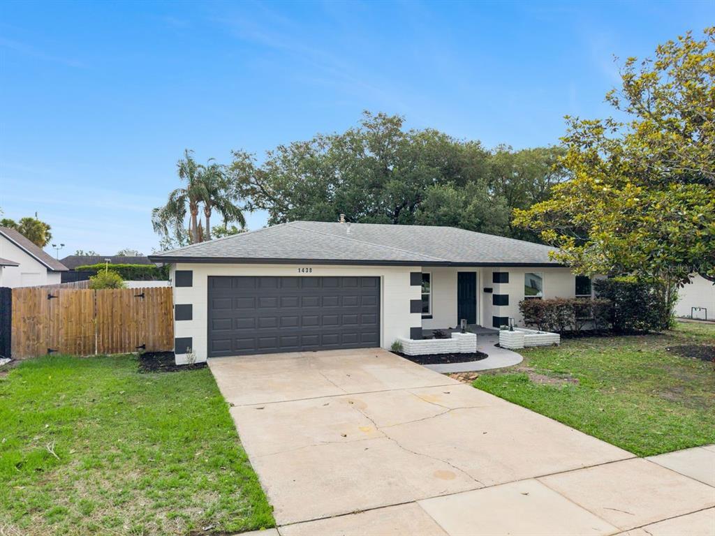 A single-story house with a white exterior, dark garage door, and a concrete driveway — 1438 TIERRA CIRCLE, WINTER PARK, FL