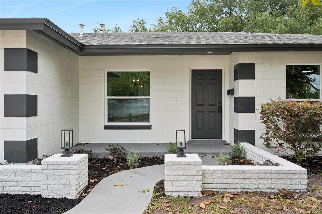 The exterior of a white concrete block house features a dark front door and walkway — 1438 TIERRA CIRCLE, WINTER PARK, FL